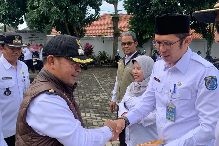 PENGHARGAAN :  Camat Bojongsari, Rijal Farhan (kiri) saat menyerahkan piagam raihan PBB tertinggi se Kota Depok pada Plt. Lurah Duren Mekar, Ari Andriana (kanan), Rabu (15/1/2025).  (RISKY DWI LESTARI/RADAR DEPOK)