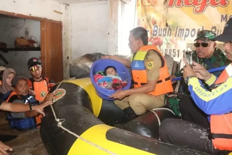 Wabup Jaro Ade mengevakuasi bayi korban banjir menggunakan bak. 