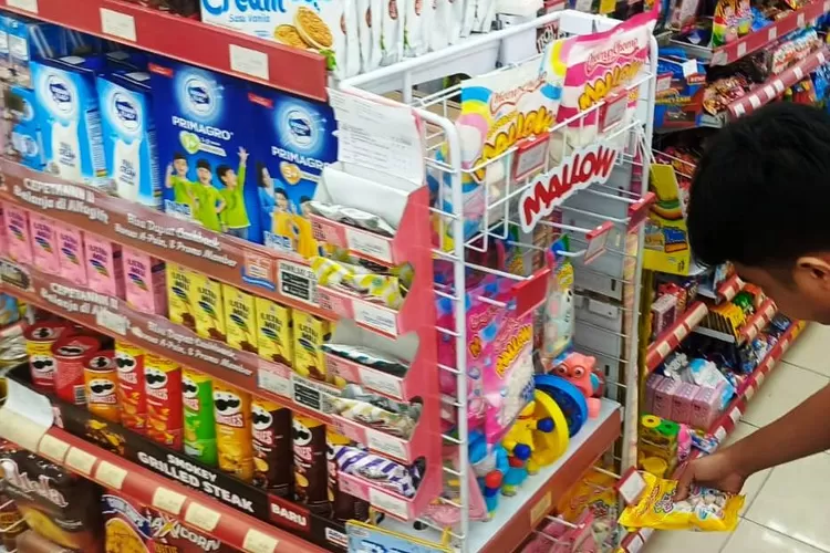 BERDAGANG : Salah satu karyawan minimarket di Kota Depok menunjukan marshmallow yang aman dari unsur babi, Minggu (27/4). (ALDY RAMA/RADAR DEPOK)
