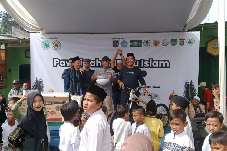 Ketua Panitia Gebyar Muharram, Indra Muliana, Ketua DMI Kelurahan Harjamukti, Cece Saepudin membagikan doorprize kepada warga pada kegiatan Gebyar Muharram, di halaman Masjit At-Taqwa, Kelurahan Harjamukti, Kecamatan Cimanggis, Kota Depok, Sabtu (28/6). (AGNESYA WIANDA/RADAR DEPOK)