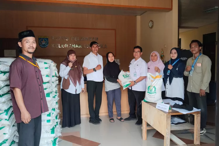 PENDISTRIBUSIAN : Sekretaris Kelurahan Cinangka Hendrik Sugianto (sebelah kanan warga penerima manfaat) yang memberikan langsung penyaluran bantuan pangan (bapang) yang diberikan langsung untuk penerima manfaat di Kelurahan Cinangka, Kecamatan Sawangan, Rabu (6/8) Siang.  (RISKY DWI LESTARI/RADAR DEPOK)