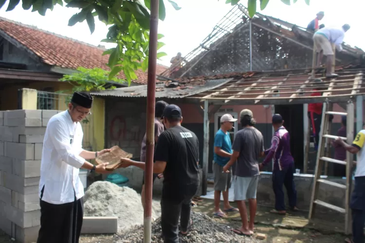 Lurah Pengasinan Ari Andriana Wijaya, dan warga setempat saat bergotong royong memperbaiki rumah rusak milik Ena (81) di RT2/5, Kelurahan Pengasinan Kecamatan Sawangan, Kota Depok, Rabu (22/10). (RISKY DWI LESTARI/RADAR DEPOK)