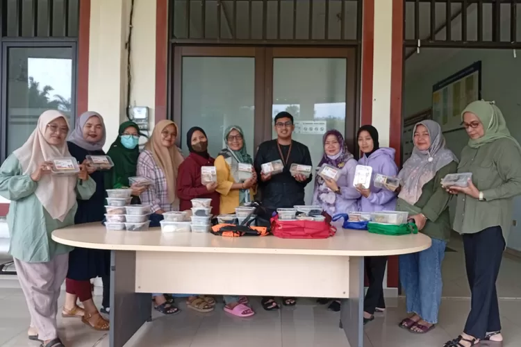Kepala Seksi Kemasyarakatan dan Pelayanan Kelurahan Sawangan, Syafrurrazi (baju pangsi hitam) bersama kader berfoto bersama sebelum mendistribusikan Pembagian Makanan Tambahan (PMT) di kantor Kelurahan Sawangan, Kecamatan Sawangan, Kota Depok, Kamis (6/11). (RISKY DWI LESTARI/RADAR DEPOK)