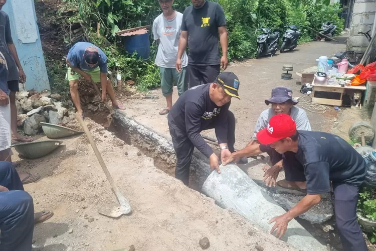 Lurah Sawangan, Fahrudin Ali Ahmad (Lurah Are) saat mengikuti langsung pemasangan U-Ditch drainase di RT1/2, Kelurahan Sawangan, Kecamatan Sawangan (Bertopi hitam sebelah kiri) bergotong royong bersama warga, Minggu (14/12).  (RISKY DWI LESTARI/RADAR DEPOK)