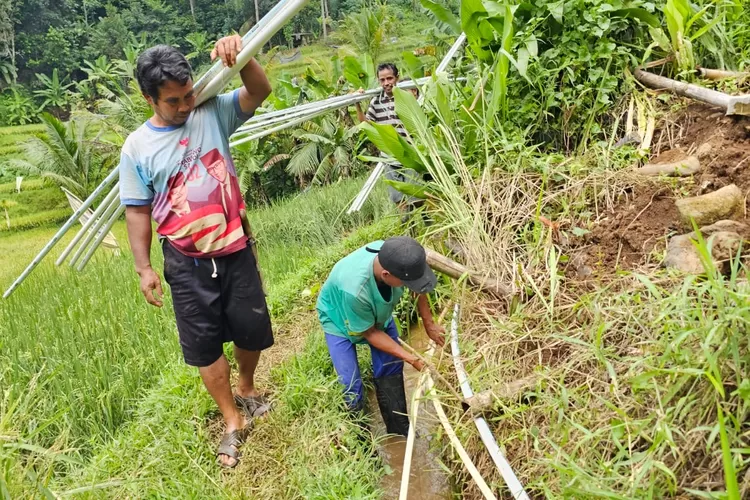 Gotong royong tim AQUA bersama masyarakat Cipondok untuk mengalirkan air bersih.