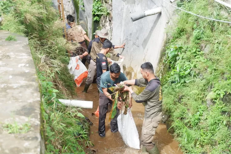 Danramil 0621-12 menggelar kegiatan Karya Bakti TNI melalui gotong royong dan kerja bakti, dengan membersihkan tumpukan sampah dan ranting di aliran sungai. (Foto: Anto)