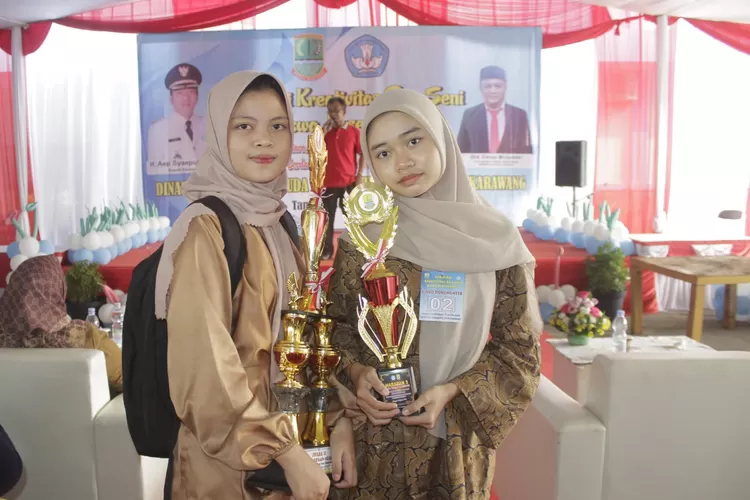 Siswi PKBM Kaliber Kalihurif Karawang Perlihatkan Piala hasil juara (Samsudin/Metropolitan)