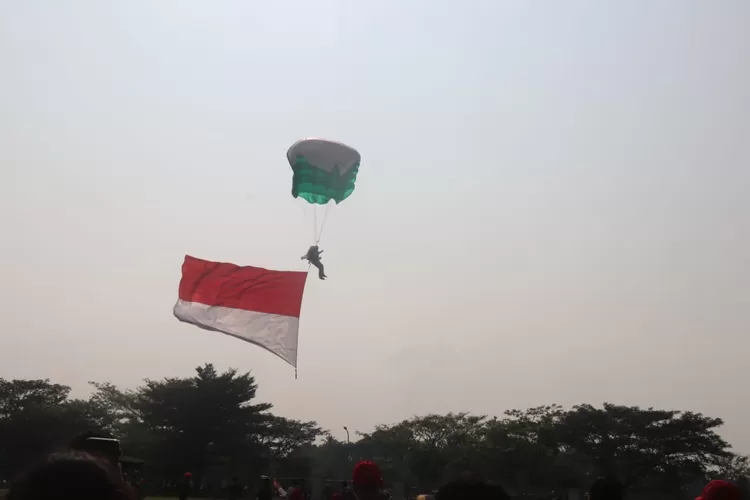 Aksi terjun payung dengan bendera merah putih membuka Kirab Merah Putih di Lapangan Tegar Beriman, Cibinong, Minggu, 11 Agustus 2024. (Ist)