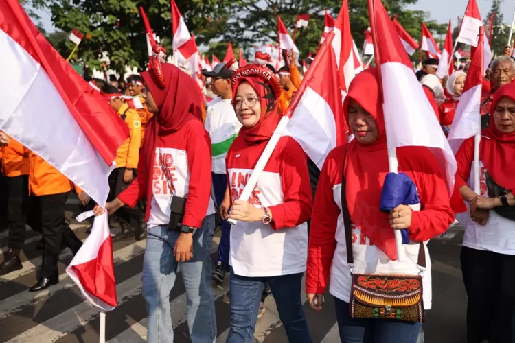 Warga membawa bendera mengikuti kirab merah putih di Jalan Tegar Beriman, Cibinong menuju Stadion Pakansari, Minggu, 11 Agustus 2024. (Devina)