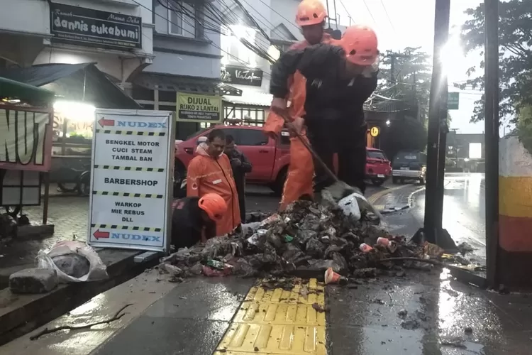 Petugas BPBD Kota sukabumi, saat memperbaiki selokan mampet yang menyebabkan banjir. (Satiri)