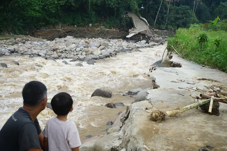 Warga melihat jembatan penghubung terputus imbas bencana banjir di Desa Cipayung Girang, Kecamatan Megamendung, Kabupaten Bogor, Senin, 3 Maret 2025. (Arifin - Metropolitan)