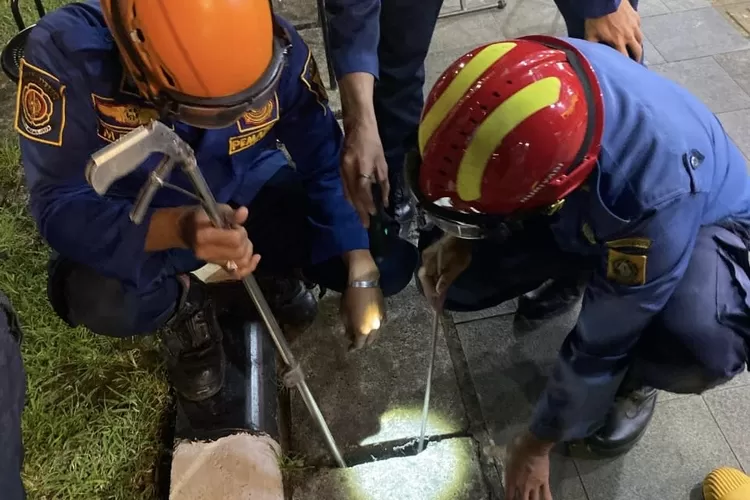 Petugas Damkar mengevakuasi HP warga yang masuk ke dalam got di Jalan Raya Stadion Pakansari, Kecamatan Cibinong, Kabupaten Bogor. (Damkar Kabupaten Bogor)
