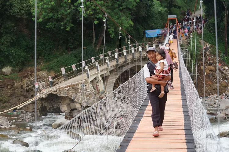 Warga saat melintas di Jembatan Perintis yang dibangun Eiger Adventure Land di Desa Cipayung,&nbsp;Kecamatan Megamendung, Kabupaten Bogor, Jumat, 21 Maret 2025. Jembatan penghubung dua kecamatan tersebut sempat terputus akibat banjir. (Arifin - Metropolitan)
