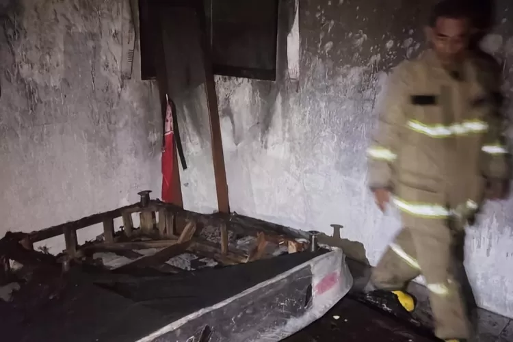 Petugas mengecek kondisi api di lokasi rumah warga yang mengalami kebakaran. 