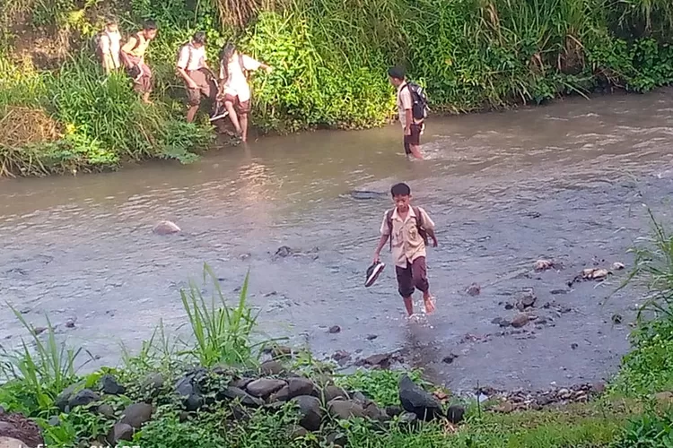 Pelajar di Desa Petir, Kecamatan Dramaga, Kabupaten Bogor terpaksa menyeberangi sungai untuk bisa sampai ke sekolah, Senin, 14 April 2025. (Ade)