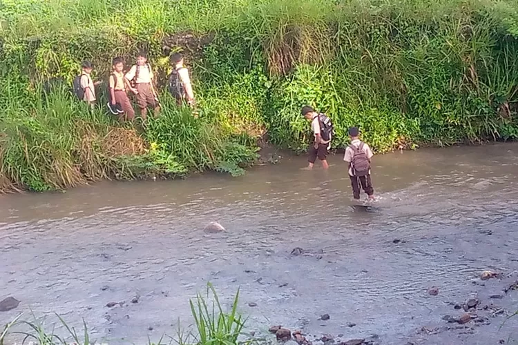 Pelajar di Desa Petir, Kecamatan Dramaga, Kabupaten Bogor terpaksa menyeberangi sungai untuk bisa sampai ke sekolah, Senin, 14 April 2025. (Ade)