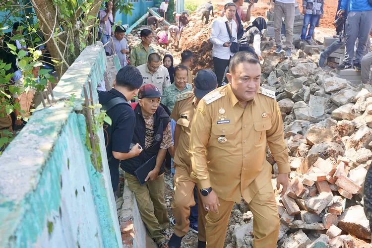 Bupati Bogor Rudy Susmanto berjalan menyusuri tembok SDN Cipayung 01 Kelurahan Tengah, Cibinong yang ambruk imbas pembangunan perumahan, Senin, 5 Mei 2025.                                (Arifin - Metropolitan)