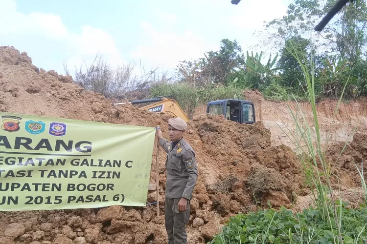 Satpol PP memasang spanduk larangan galian tanah di lahn sitaan Kejagung di Parungpanjang, Kabupaten Bogor. (Nasir)