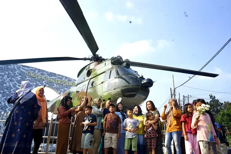 Sejumlah warga berfoto di depan Tugu Helikopter SA-330 Puma di Simpang Pakansari, Cibinong, Kabupaten Bogor, Jumat, 25 Juli 2025. (Arifin - Metropolitan)