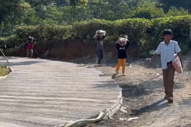 Warga melintas di Jalan Nirmala, Desa Malasari, Kecamatan Nanggung, Kabupaten Bogor yang tengah dibangun Pemkab Bogor, Rabu, 23 Juli 2025. (Panca Aji)