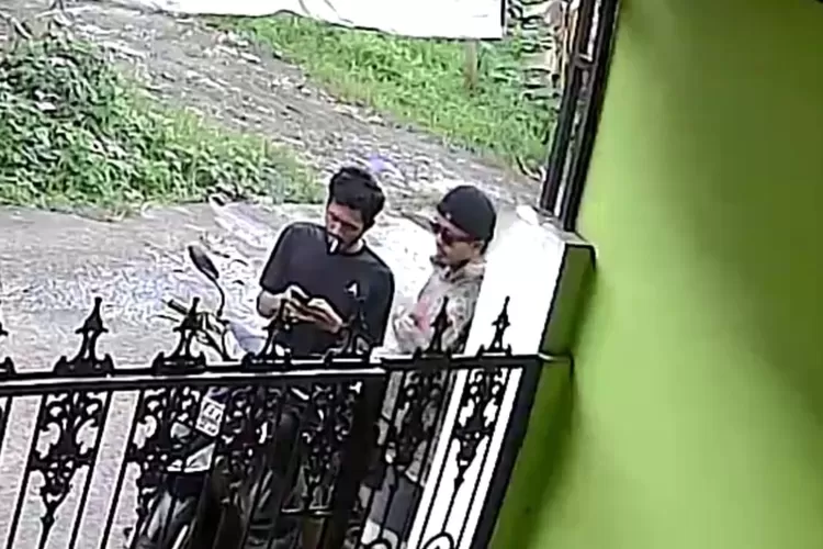 Tangkapan layar dua orang yang menempelkan barang diduga narkoba di salah satu banner yang ada di perkampungan warga. 