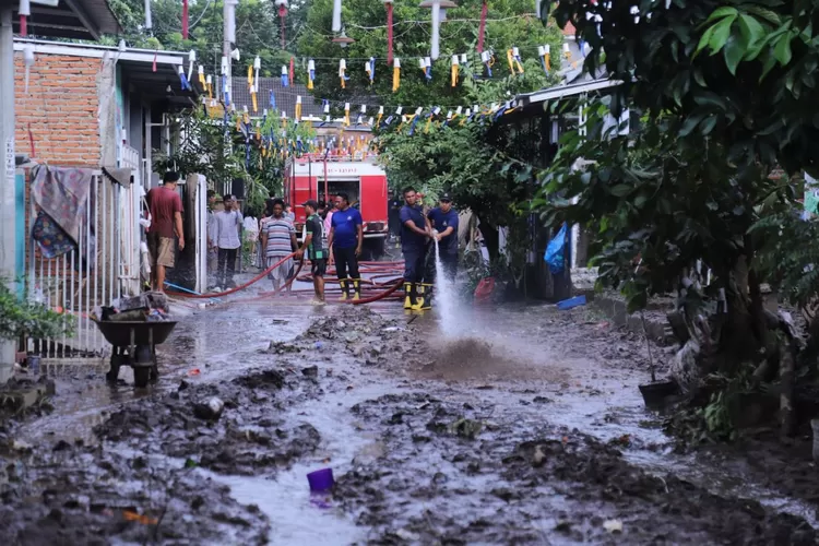 Anggota BPBD Jember saat membersihkan kawasan Perumahan Villa Indah Tegal Besar Jember yang dilanda banjir.  (Diskominfo Jember)