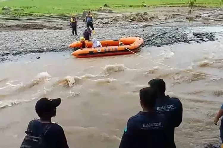 Sejumlah warga menaiki perahu karet akibat jembatan putus sehingga menyebabkan warga terisolir. 