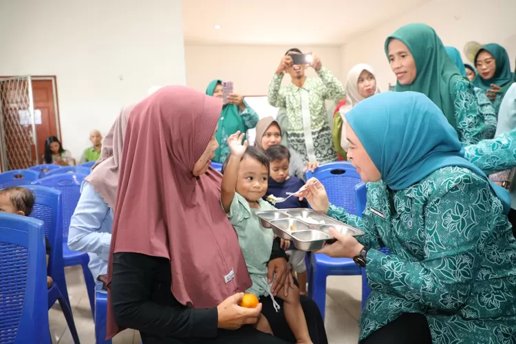 Puluhan ibu hamil dan balita berkumpul, sebagian membawa anak kecil yang sesekali berlarian. Di meja panjang, paket berisi susu, telur, biskuit, hingga kacang hijau tersusun rapi, menunggu dibagikan. (dok)