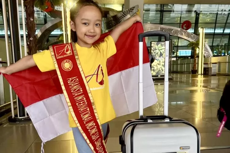 Aisyah Zahira Putri Ismail membentangkan bendera Merah Putih ketika hendak bertolak ke Sinagpura mengikuti Event AsiaNista International Tingkat Asia - Foto: Dokumen Pribadi     