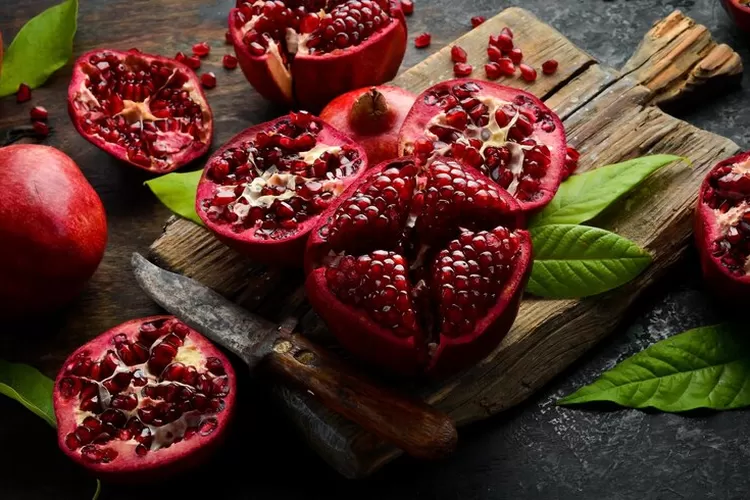 segar dari buah delima yang terbelah menunjukkan biji-biji merahnya yang berkilau, menggambarkan sumber alami antioksidan dan vitamin yang bermanfaat untuk kesehatan jantung dan kulit
