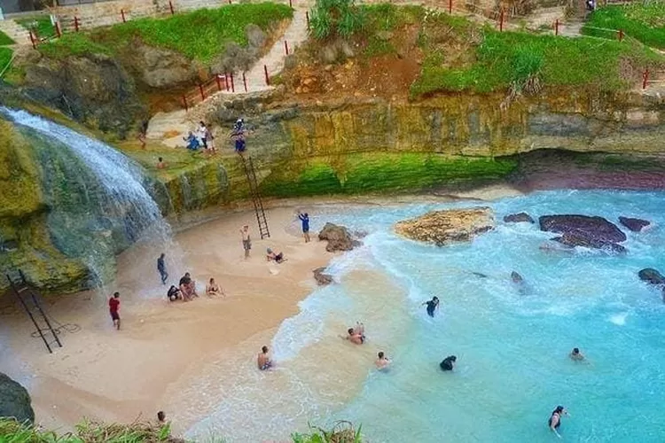 Keindahan air terjun di Pantai Banyu Tibo yang mengalir langsung ke laut biru jernih, menciptakan pemandangan yang memukau