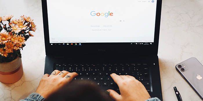 Seseorang membuka situs web Google di laptop. Ilustrasi cara buat akun Google di laptop dan PC.