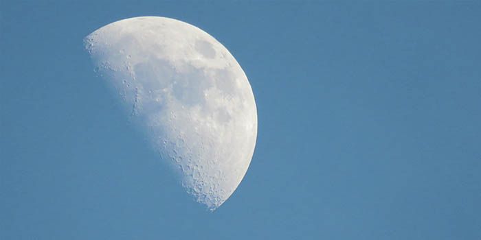 Bulan terlihat di siang hari saat langit masih biru.