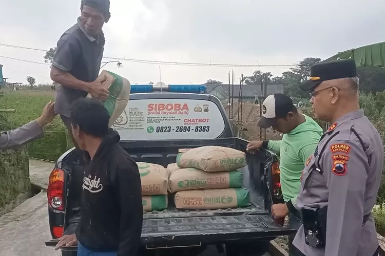 Polisi bersama pekerja menurunkan semen bantuan dari mobil untuk warga di daerah Gedangan, Cepogo, Boyolali yang menjadi korban tanah longsor di lereng Gunung Merapi-Merbabu.(SMSolo/dok)