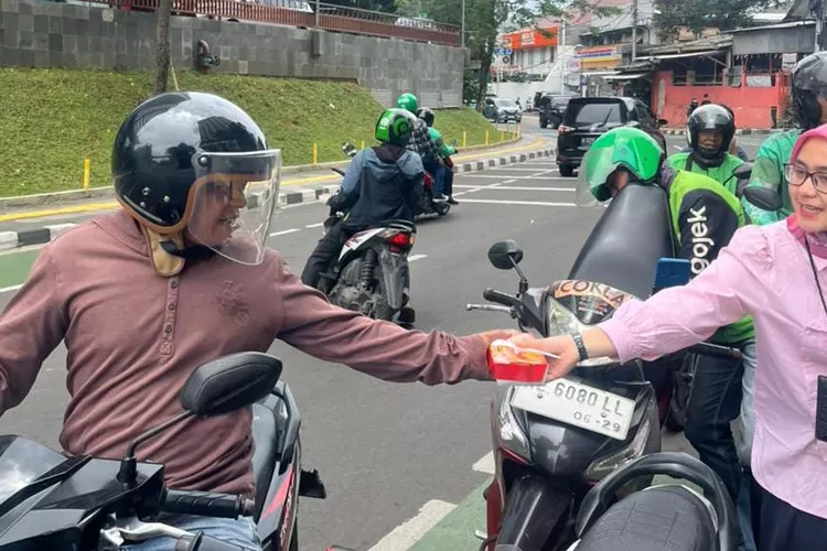 Pegawai BRI KC Pancoran saat membagikan makanan dalam program Jumat Berkah kepada pengendara yang melintas sekitar kantor.  (DOKUMEN BRI)