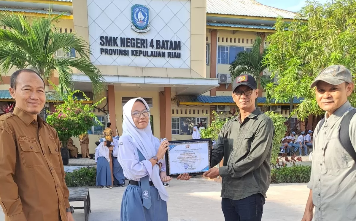 Ketua PWI Batam, M.A. Khafi Ansari didampingi Pengurus PWI Batam dan Kepala Sekolah SMKN 4 Batam, Abdul Mukti menyerahkan piagam penghargaan kepada Nada Salsabila Kamil. (M Kamil)