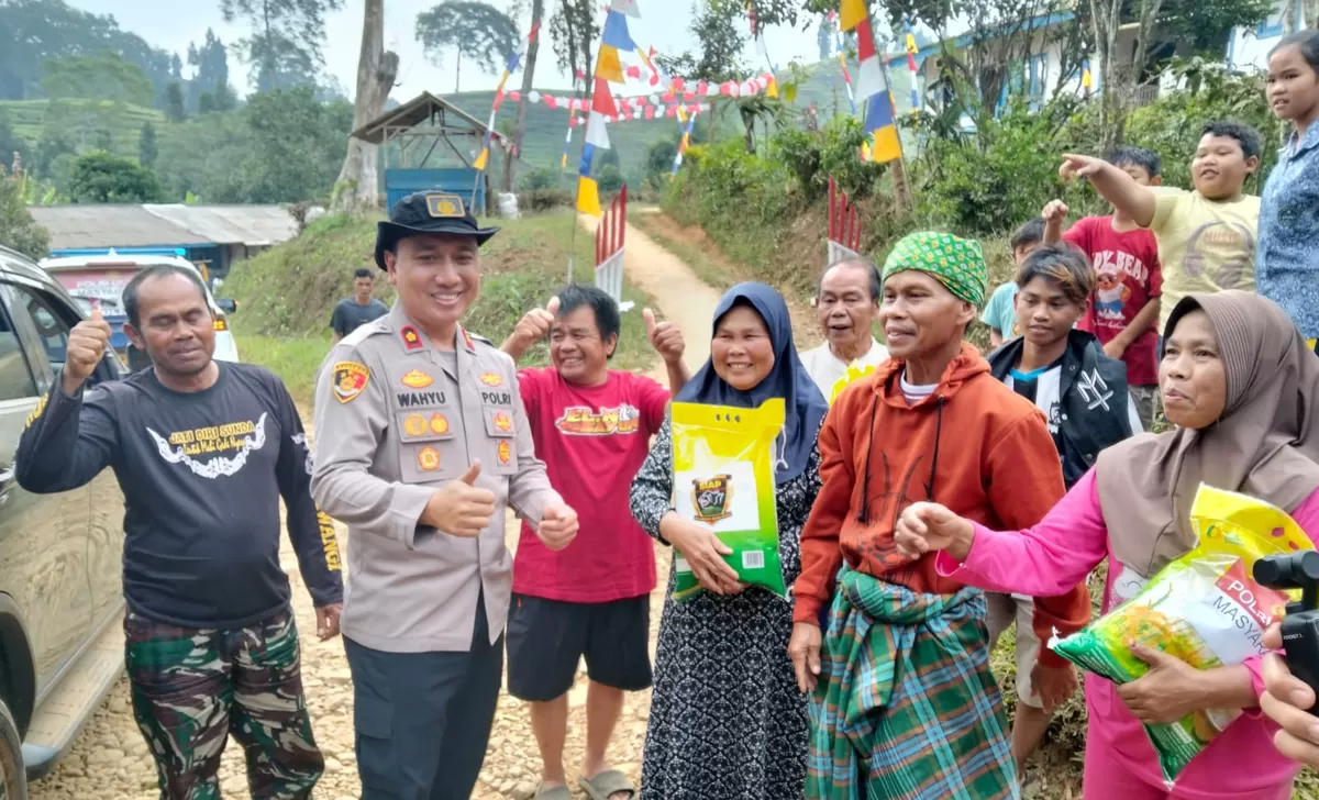 Wakapolres Cianjur Kompol Wahyu Maduransyah Putra membagikan bantuan beras serta bingkisan makanan ringan kepada warga dan anak-anak di kawasan perbatasan Kabupaten Cianjur dengan Bandung Selatan. (FOTO: Ist)