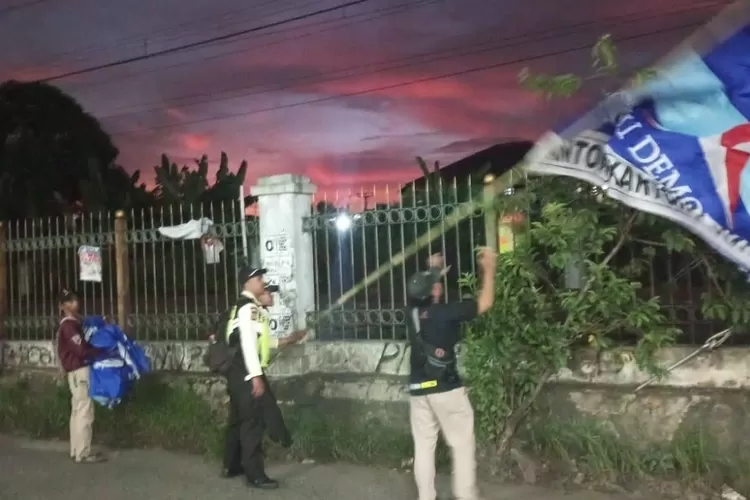 Panwascam dan Satpol PP Kecamatan Bojonggede menertibkan sejumlah bendera partai yang terpasang di samping rel kereta, karena dikhawatirkan menganggu sinyal KRL dan pengguna jalan. (Foto: Haerudin)