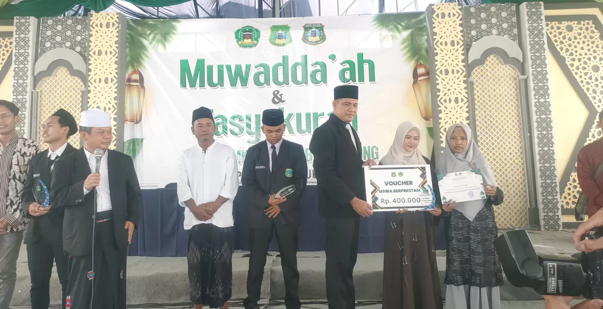 Pengasuh Ponpes Falahul Muhibbing KH Nur Hadi (tiga dari kiri) atau yang disapa Mbah Bolong menyaksikan siswa/santri berprestasi menerima hadiah secara simbolis berupa nilai sejumlah uang . (SketsaNusantara.id/As'ad Choirudin )