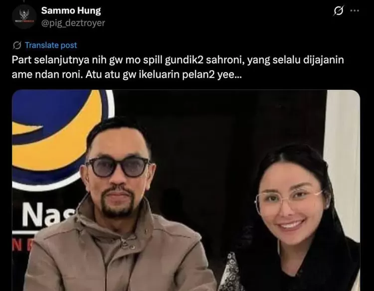 Ahmad Sahroni bersama seorang wanita di depan spanduk NasDem.