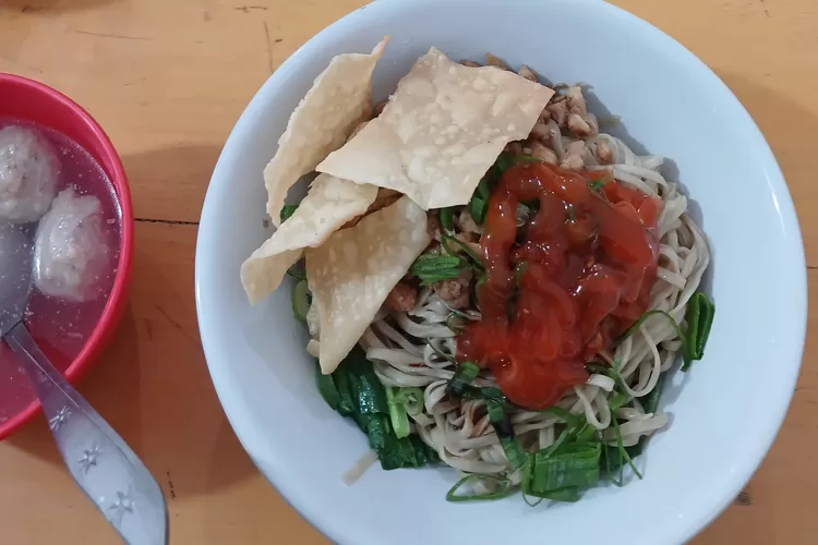 Semangkuk mie ayam lengkap dengan sambal, sayur segar, dan kerupuk pangsit yang renyah, menjadi sajian sederhana yang selalu berhasil memikat selera. Ditambah kuah bakso hangat di sisi, inilah definisi kenyamanan dalam satu meja makan. (Foto - Dheandra Maisha Ramadhany.)
