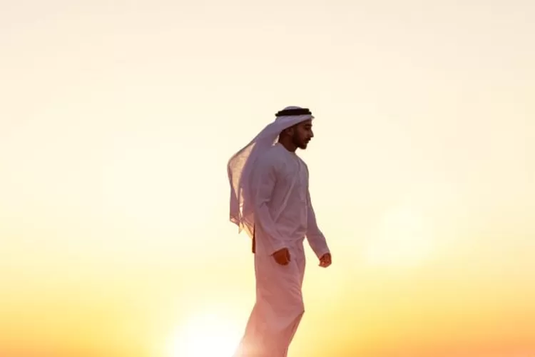 Middle Eastern man in a traditional Arab dress in the desert at sunset (LeoPatrizi)