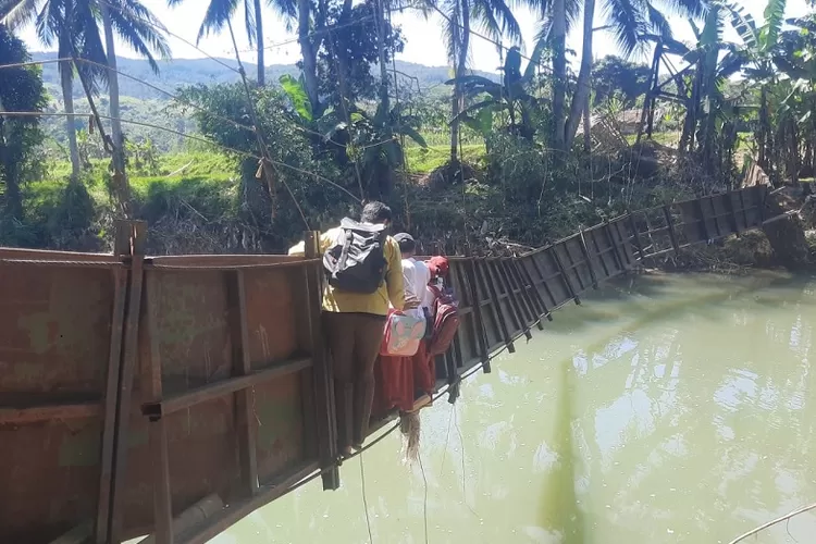 PENUH RISIKO: Sejumlah pelajar meniti jembatan gantung rusak dari Desa Neglasari, Lengkong, ke Desa Bantar Panjang, Sukabumi (23/7). (NANDI/RADAR SUKABUMI)