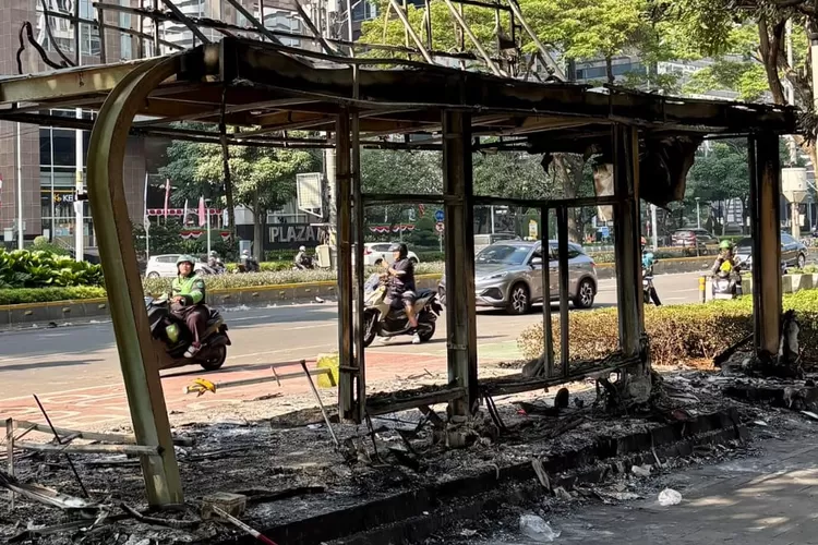 Foto menunjukkan halte TransJakarta yang hangus terbakar, menyisakan rangka dan puing di tengah lalu lintas kota. (Foto/X - @rendrasd.)
