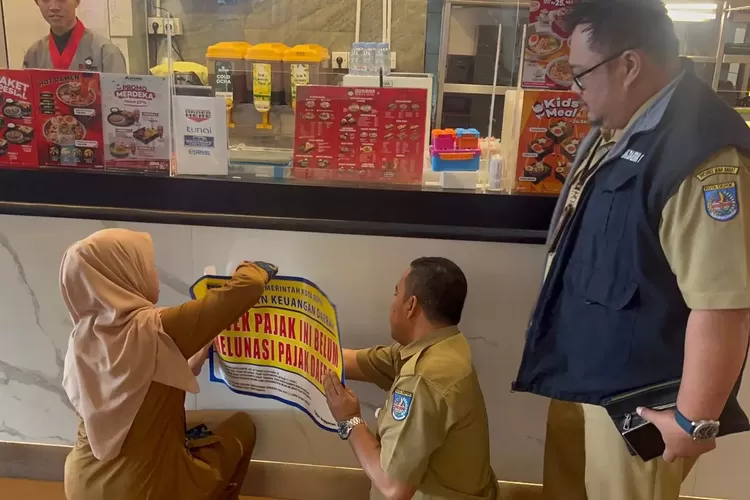 BKD Kota Depok menempelkan stiker kepada objek pajak yang memiliki tunggakan, di salah satu restoran Kota Depok. (DOK BKD DEPOK)