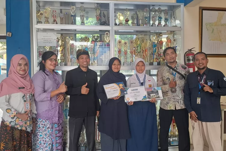 Penyerahan piagam beserta medali kepada Almira Shafa, siswa kelas IX dari Kepala SMPN 26 Depok, Ahmad Sujai, di halaman sekolah, yang terletak di Jalan Mangga, Kelurahan/Kecamatan Beji.  (ANDIKA EKA/RADAR DEPOK)