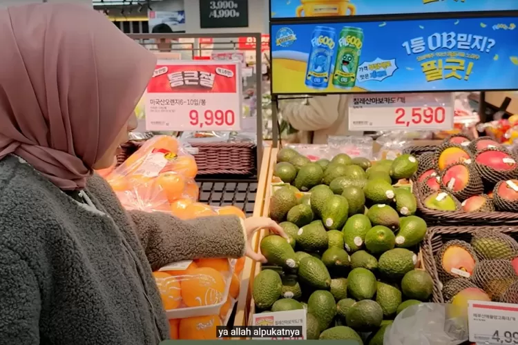  Seorang pembeli tengah memilih alpukat segar di salah satu supermarket Korea Selatan saat berbelanja kebutuhan Ramadan. Penataan buah yang rapi dan beragam harga menarik menjadi daya tarik tersendiri bagi konsumen, meski tetap perlu cermat agar tidak boros. (Foto/YouTube - @BiancaKartika.)