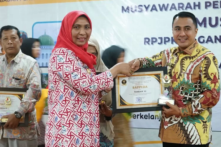 Fitriany Farhas, AP., S.Sos., M.Si    Pejabat (Pj) Bupati Nagan Raya saat menyerahkan penghargaan kepada Kepala Bappeda Rahmattullah (KLIKANGGARAN )