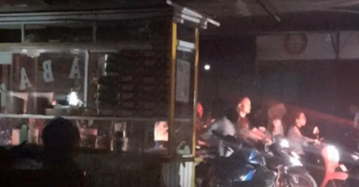 Salah satu pedagang di pinggir jalan raya kota Medan berjualan hanya diterangi lampu kendaraan yang lewat. 