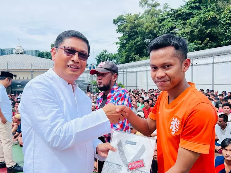 Kepala Rutan Kelas I Depok, Lamarta Surbakti, membagikan baju muslim kepada warga binaan. 